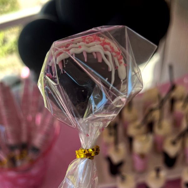 Chocolate cake pop with white drizzle and pink sprinkles