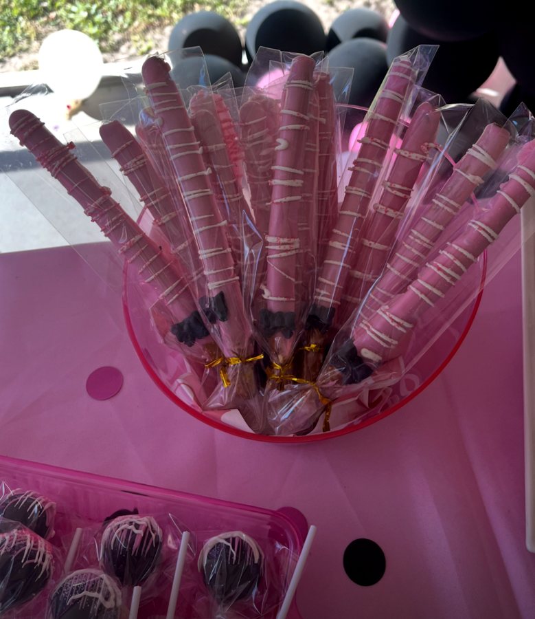 Bucket of pink chocolate-dipped pretzel rods at a party table